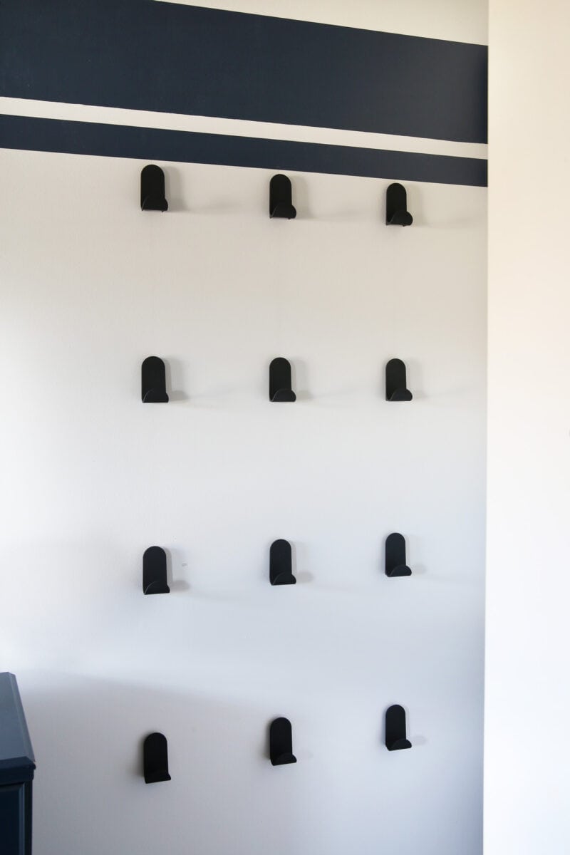 12 black j-hooks hanging on the wall in a boys' bedroom