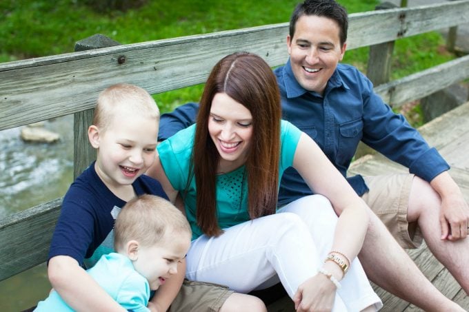 Dad, mom, and two sons sitting on a bridge