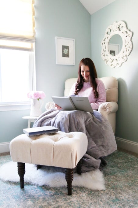 Woman in a pink sweater sitting in a chair, looking at a book