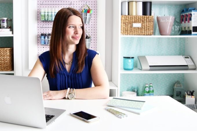 Woman in a purple dress sitting at a desk with a laptop in front of her