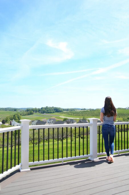 woman standing on a deck looking at a view of rolling hills