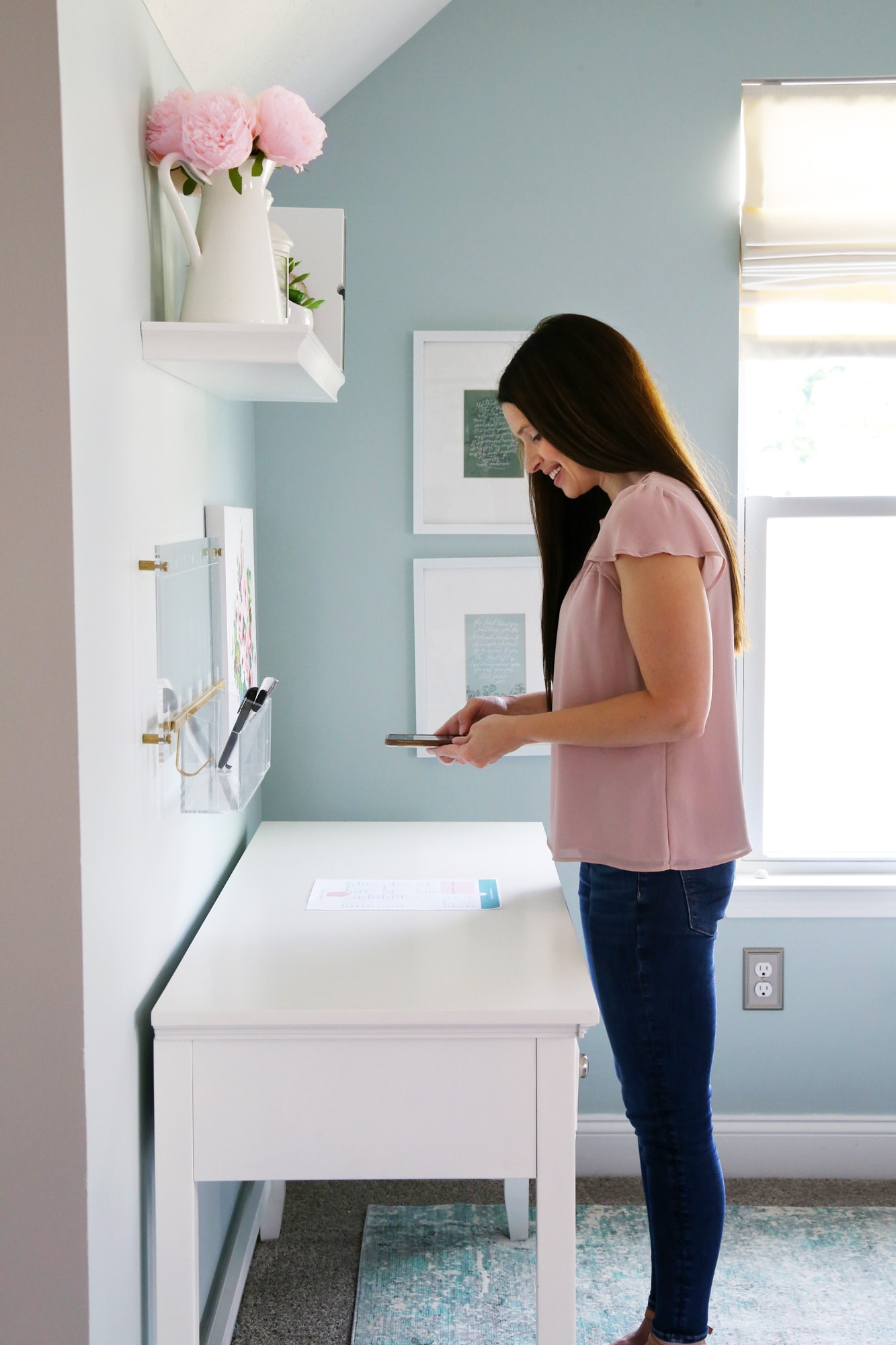 Woman in pink shirt and jeans scanning a piece of paper with her phone