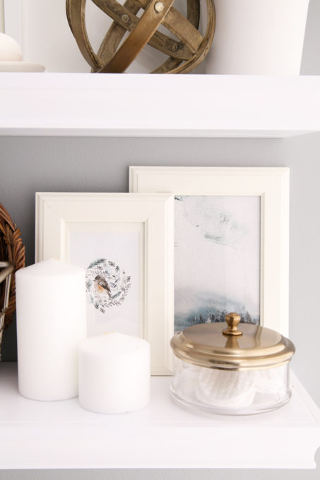 Two Inexpensive Art Prints on a Shelf in the Bathroom