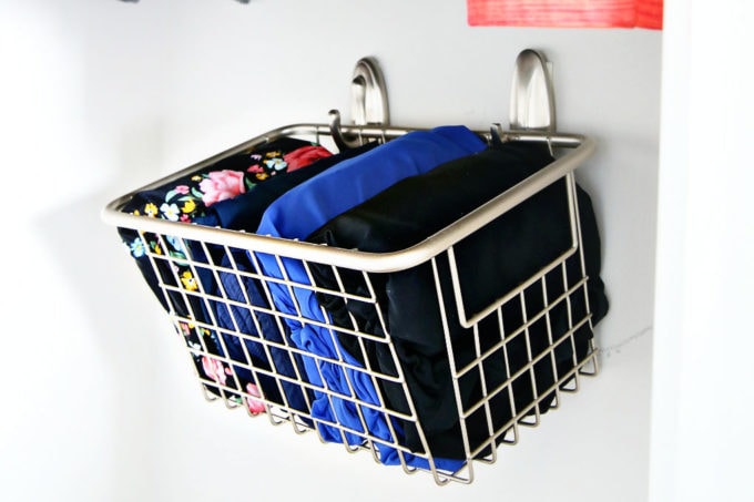 Bathing suits in wire basket hung on the wall of a small closet with Command hooks, closet ideas