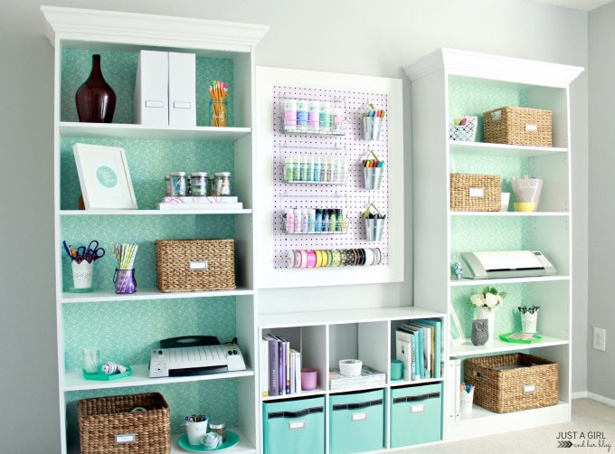 Built-in bookshelves with crown molding and a wrapping paper backdrop holding home office accessories and craft supplies