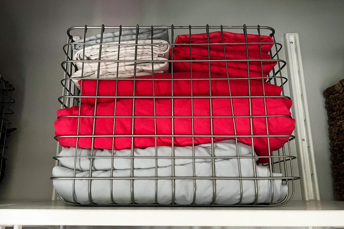 A wire bin holding sheets and pillowcases in an organized kids room