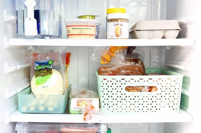 the top and middle refrigerator shelves organized with a couple of bins