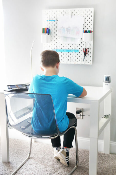 boy sitting at desk in organized playroom