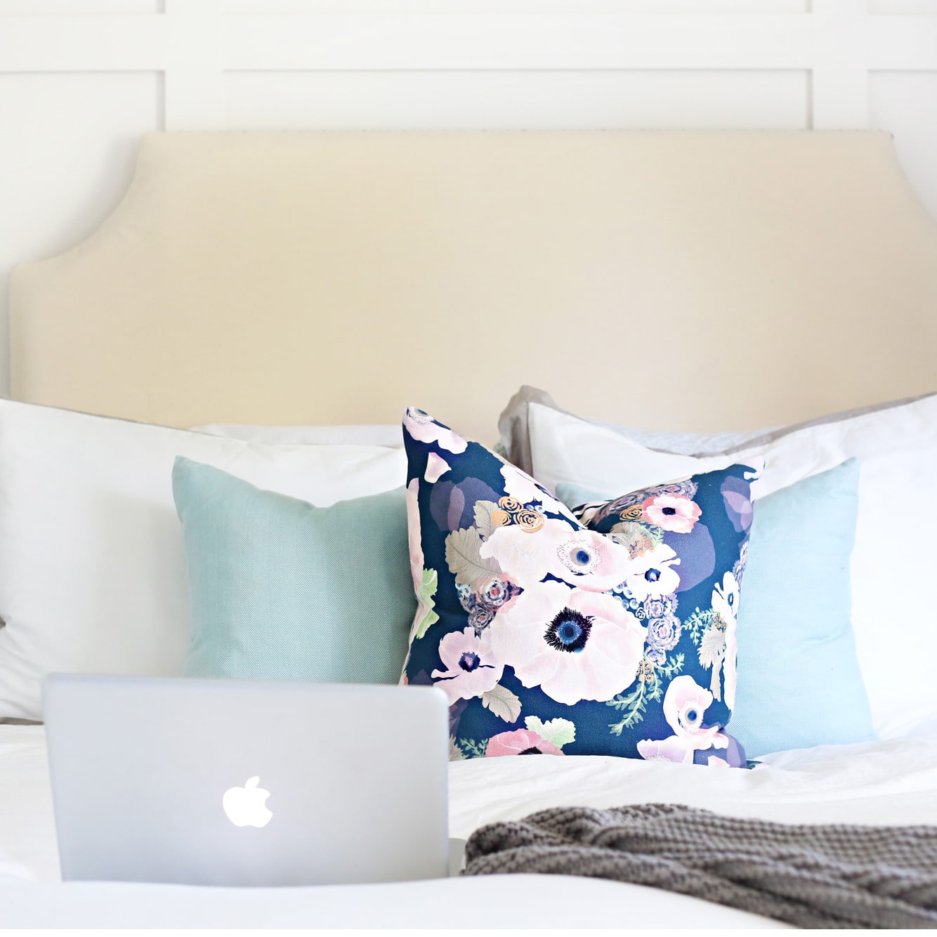 Laptop Computer Sitting on a Bed, next to a floral pillow