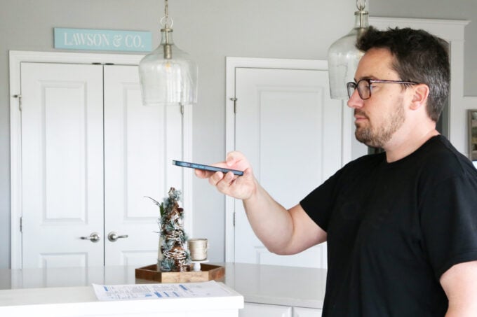 Man in a black tshirt scanning a piece of paper with his phone