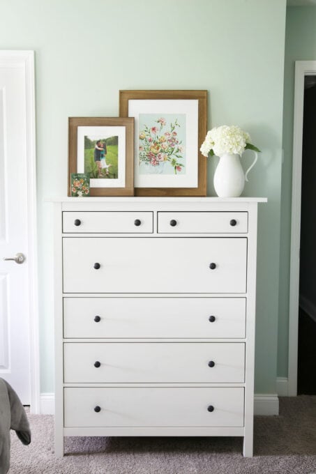 Dresser with a picture of a couple, a flower print, and a vase of white hydrangeas