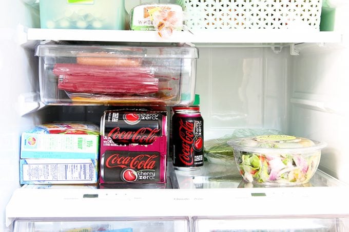 the middle shelf of the refrigerator with drinks and other food