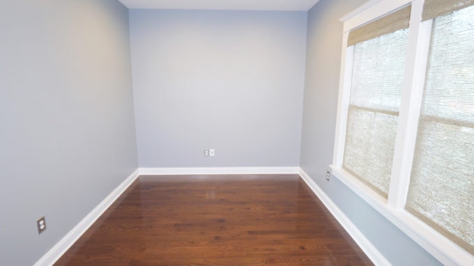 Empty home office with gray walls and bamboo shades on the windows