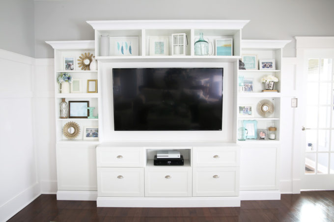 Adding Tall Decorative Objects to the Ends of Shelves for Shelf Styling on a White Entertainment Unit in the Living Room