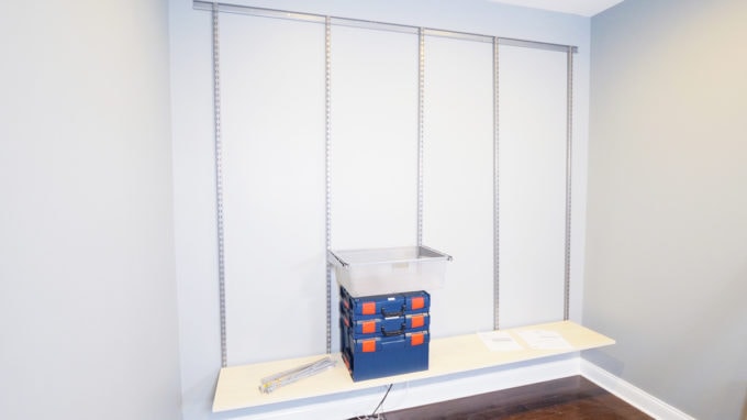 Storage Containers Sitting on an Elfa Shelving Unit from The Container Store with Sand Shelves and Platinum Uprights and Accessories that Is in the Process of Being Built