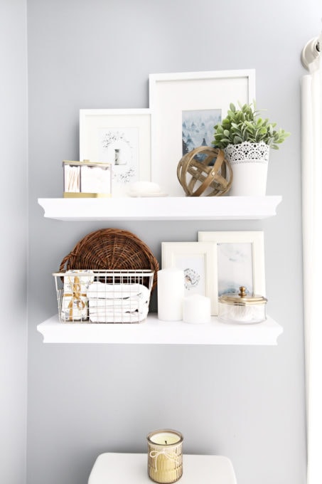 white floating shelves hanging on the bathroom wall