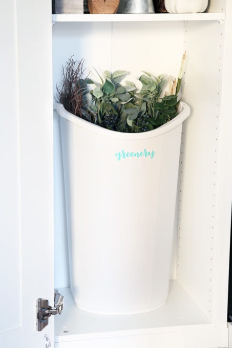 Use an inexpensive plastic trash can to store extra faux greenery.