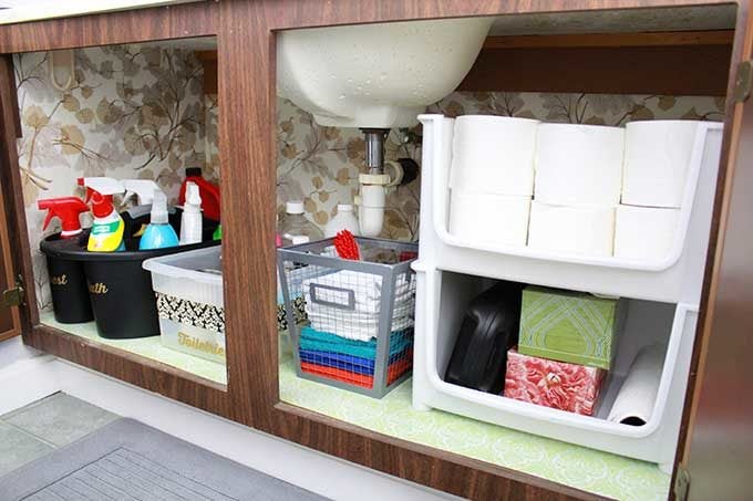 underneath the townhouse bathroom sink organized with baskets and containers.