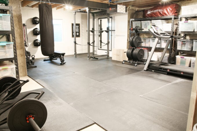 Basement home gym with rack, weights, treadmill, bench, and punching bag