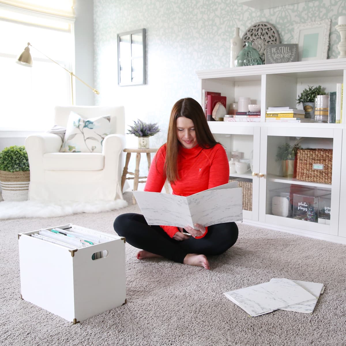 woman sitting on the floor in a home office, looking through a folder of paperwork