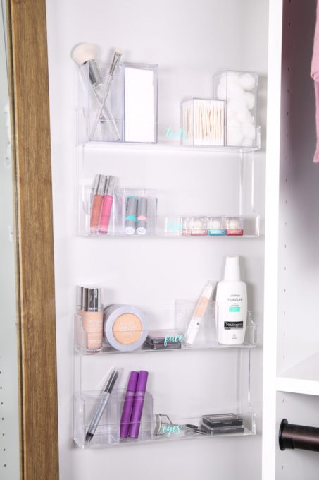 Makeup organized in spice racks on the wall of a closet to maximize vertical space