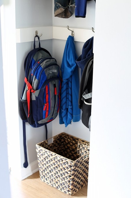 basket underneath the hanging coats and backpacks