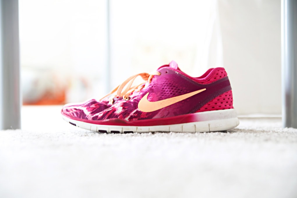 Pink Nike running shoes with an orange swoosh logo