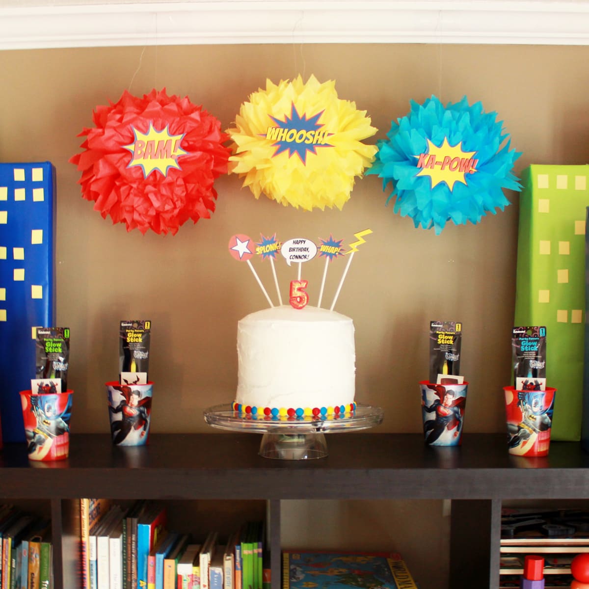 Cake and PomPom Decorations with Fight Words for a Superhero Birthday Party