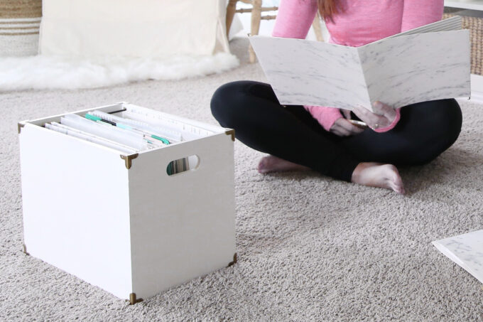 Woman looking at a folder with a crate of files sitting in front of her