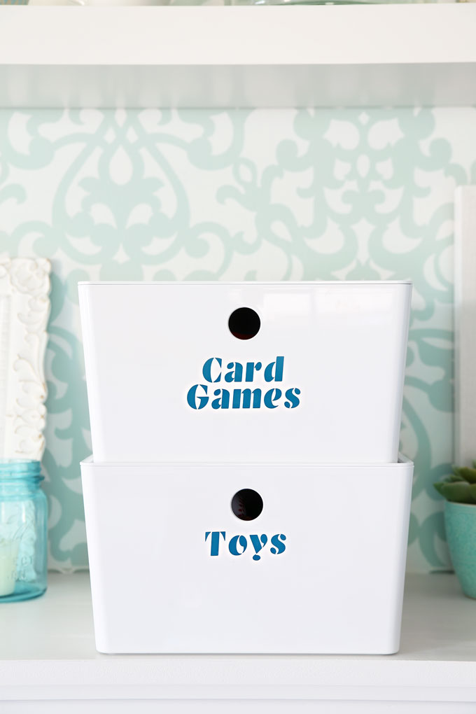 Two white bins with teal vinyl labels reading "Card Games" and "Toys"