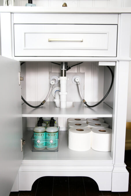 Gray Bathroom Vanity with Organized Toilet Paper and Hand Soap in a Small Powder Room