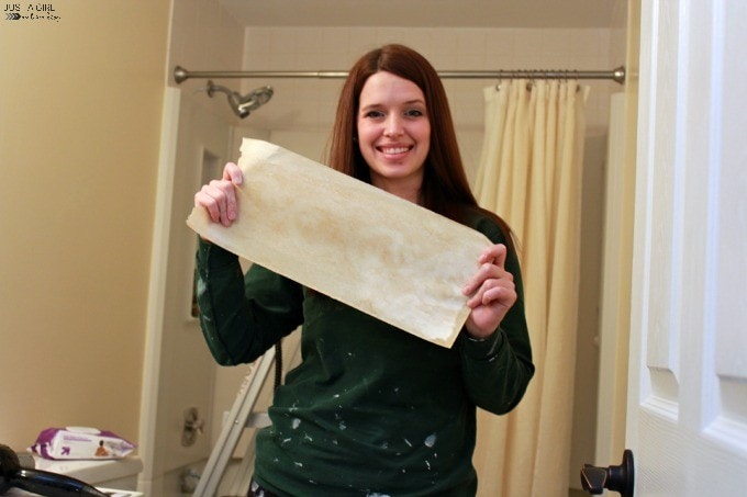 Abby holding a piece of wallpaper after using the steamer to remove it