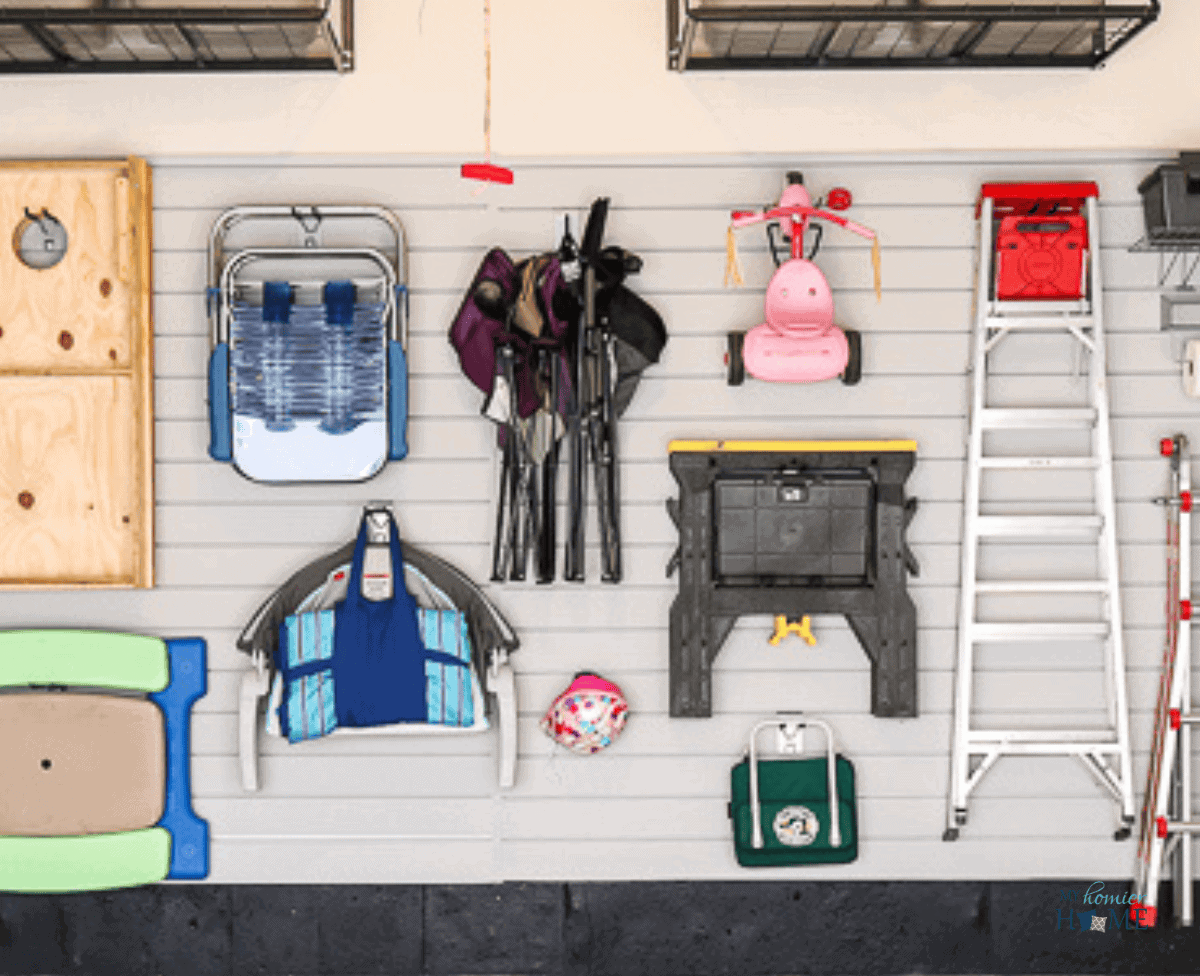 Gray slat wall with outdoor toys and equipment hanging for storage