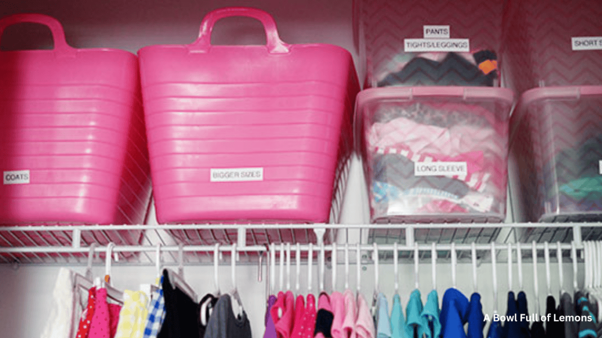 Pink bins inside a closet to help organize hand me down clothes