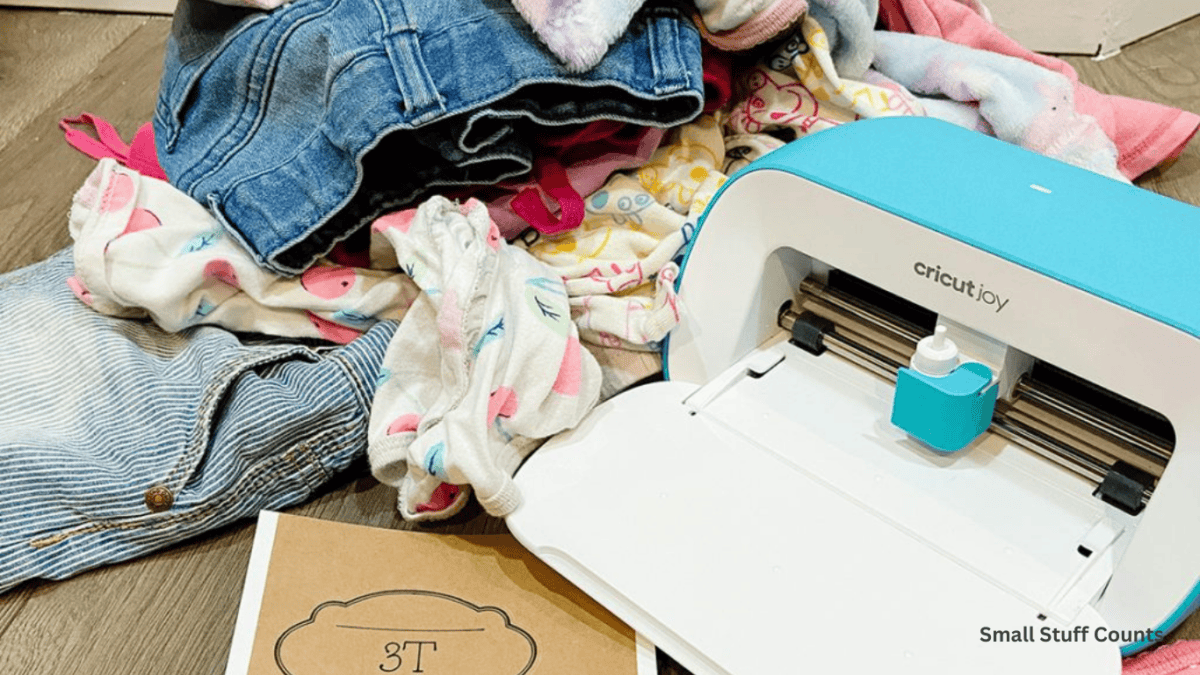 Pile of clothes and Cricut joy label maker to help organize hand me down clothes.